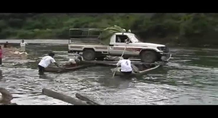 Машину сплавляют по реке на двух лодках